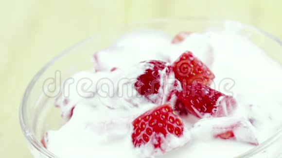 男人用勺子在透明的杯子里吃健康的草莓配上白色酸奶健康水果的概念视频的预览图