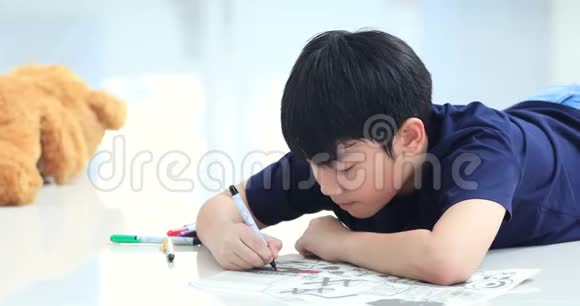 亚洲男孩在地板上休息用彩笔画画视频的预览图