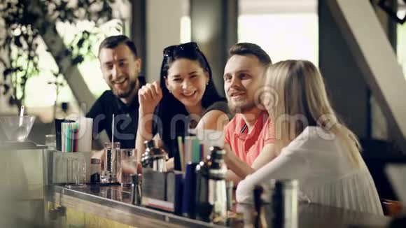 夏天四个穿着便服的年轻人正在酒吧柜台边谈笑风生两名男子和两名妇女视频的预览图