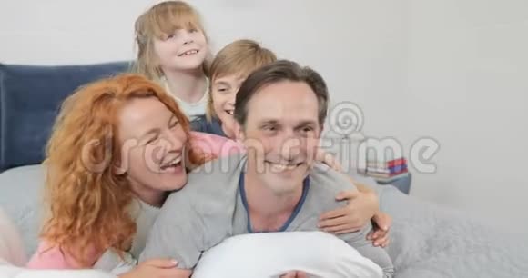 一家人开心的笑着躺在爸爸的卧室里快乐的父母和孩子在一起视频的预览图