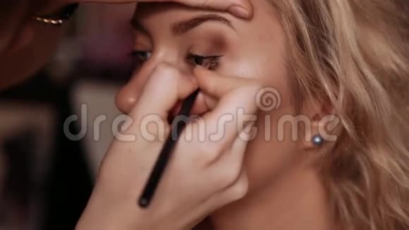 女孩化妆师在模特的眼睛上追踪睫毛的线条视频的预览图