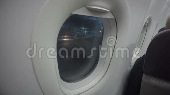 飞机乘客在机场透过飞机窗口寻找夜间航班延误视频的预览图
