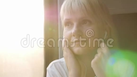 一个女人用耳机听音乐从火车上看窗外旅行和假日概念视频的预览图