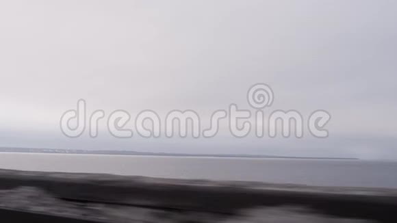 驾驶汽车沿着广阔的大海行驶冬天阴天视频的预览图
