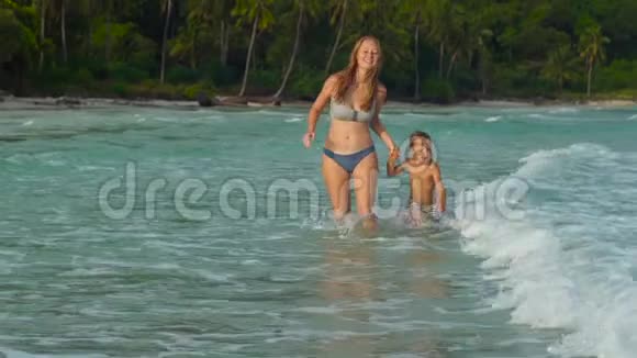 一个年轻的暴跳如雷的女人和她的儿子在海滩和海里玩得很开心视频的预览图