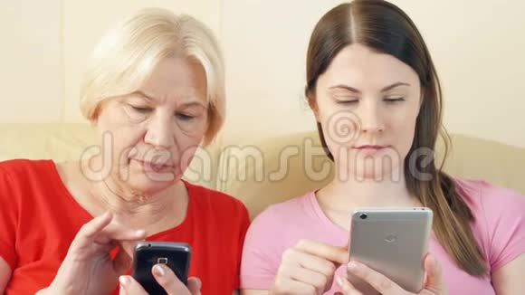 母女俩用智能手机浏览阅读老年人积极的现代生活方式视频的预览图