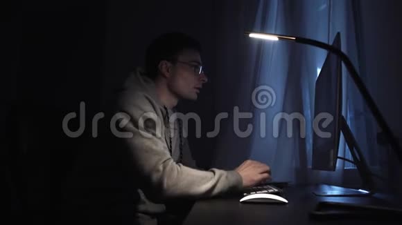 一个疲惫的年轻人晚上在电脑上工作搔额头视频的预览图
