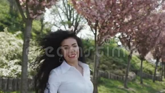 美丽的女人在盛开的公园里慢悠悠地散步视频的预览图