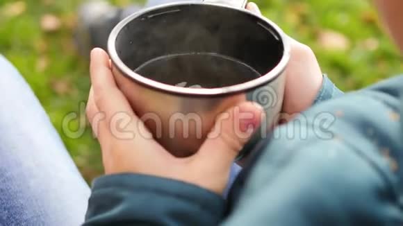 秋天公园里的家伙坐在草坪上喝热茶在新鲜的空气中散步双手特写视频的预览图