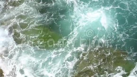 在晴朗晴朗的天气里泡沫的波浪在岩石海岸上破浪前进视频的预览图