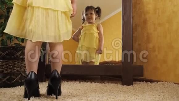 一个穿着妈妈的小女孩在镜子旁鞋子一个穿黄色连衣裙的漂亮孩子倒映在镜子里成年儿童视频的预览图