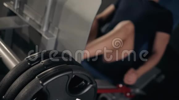 在健身俱乐部里使用印刷机的人人在模拟器里做腿上的运动侧视近景视频的预览图