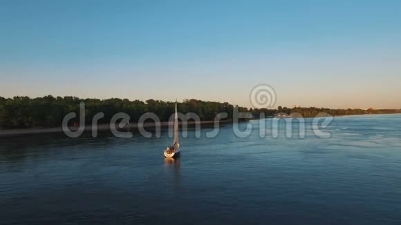 日落时分带着白帆的帆船沿着河游视频的预览图