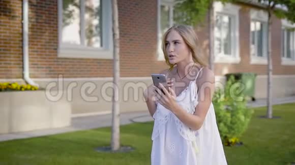 穿着白色蕾丝连衣裙的年轻有魅力的女人去散步和她的朋友在电视上聊天视频的预览图