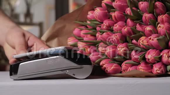 鲜花店里的郁金香非接触式付款方式时刻用手机通过终端支付买卖视频的预览图