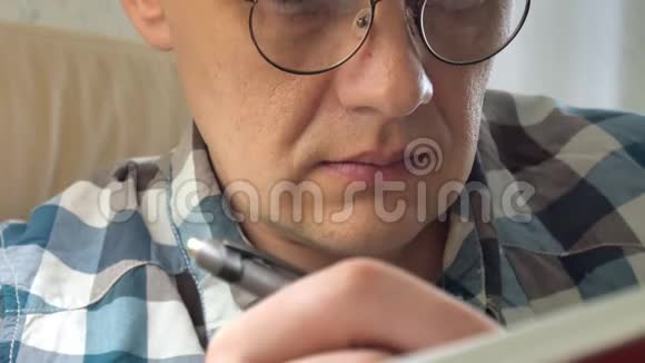 近距离拍摄一个商人拿着笔思考和笔记在笔记本上训练视频的预览图