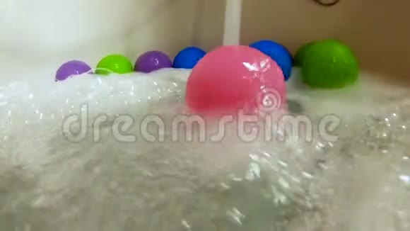 粉红色塑料球在浴缸里的水流中滚动动作缓慢视频的预览图