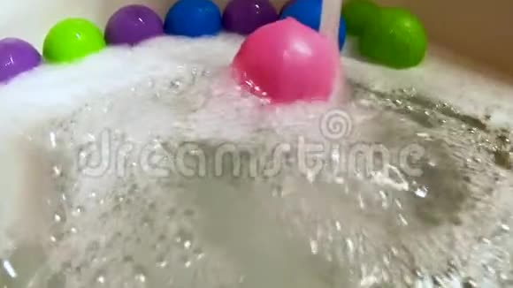 粉红色塑料球在浴缸里的水流中滚动动作缓慢视频的预览图