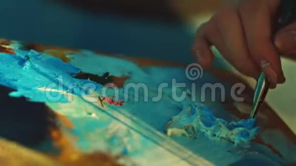 女人在艺术家调色板上混合颜料油画布上视频的预览图