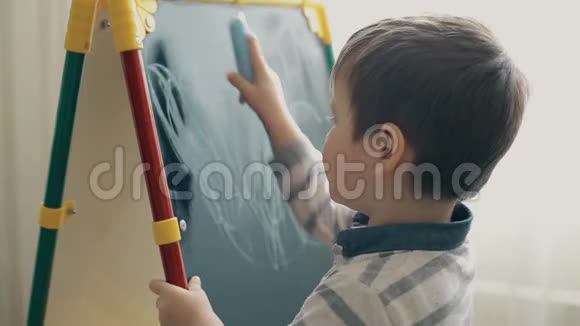 一个小孩子学会用粉笔在黑板上画画视频的预览图