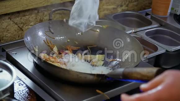 厨师把米粉放进炒菜的热锅里视频的预览图