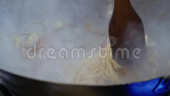 厨师把乌冬面和炒菜混合在热锅里视频的预览图