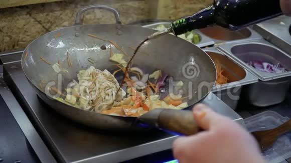 厨师在平底锅中往乌顿面和炒菜中倒入大豆和烤酱视频的预览图