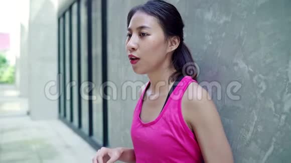 慢动作健康美丽的年轻亚洲跑步女子饮水因为在街上跑步后感到疲倦视频的预览图