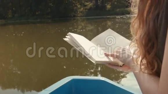 在湖上坐船看书的年轻女子视频的预览图