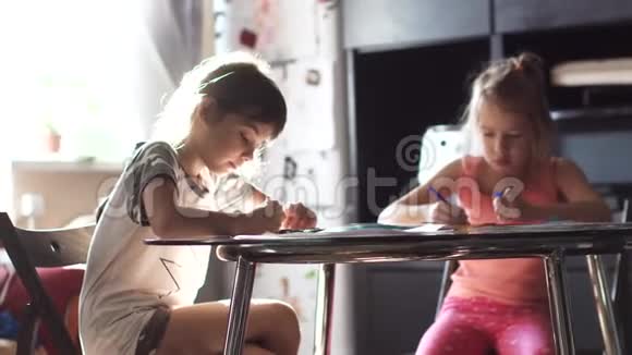 两个6岁和7岁的姐妹一起坐在桌子旁孩子们在阳光下用蜡笔画画视频的预览图