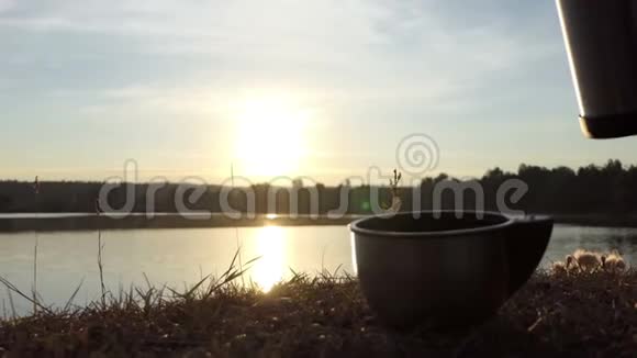 热茶是从一个烧瓶在一个杯子里倒在一个湖岸的斯洛莫视频的预览图