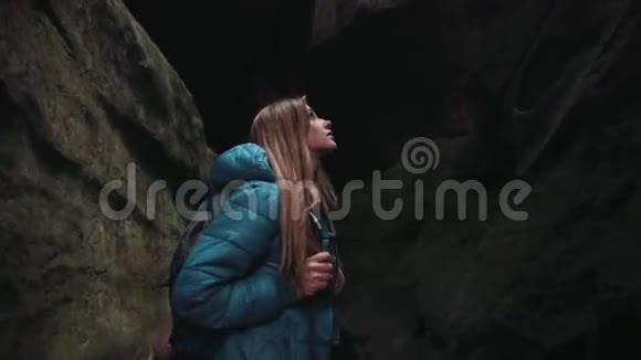 迷人的欧洲女人游客带着背包在黑暗的洞穴里行走在里面旋转观察着视频的预览图