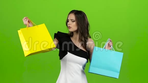 女孩留着购物袋怀疑该选择什么绿色屏幕慢动作视频的预览图