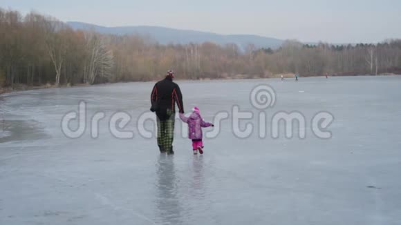 父亲和女儿学习在冰冻的湖面上滑冰视频的预览图