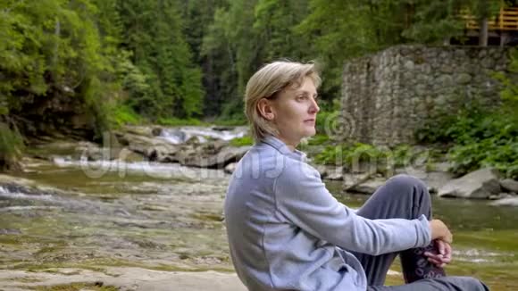 坐在山河岩石上的女人和小女孩视频的预览图
