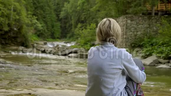 坐在山河岩石上的女人和小女孩视频的预览图