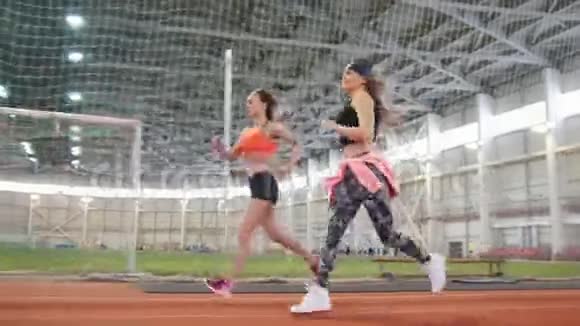 两个年轻的女运动员在室内运动场上奔跑视频的预览图