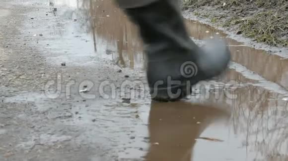 一个人穿着橡胶靴穿过泥泞的水坑视频的预览图