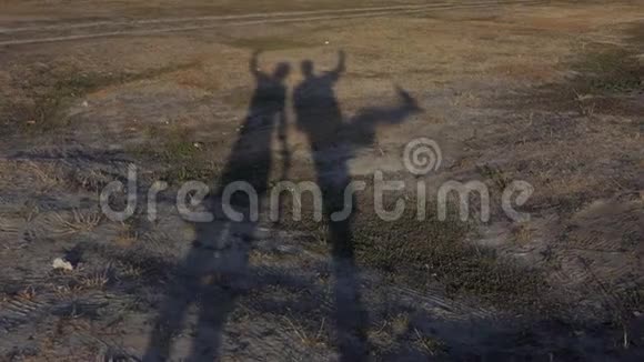 两个长长的年轻人的影子在夏天的一片土地上视频的预览图