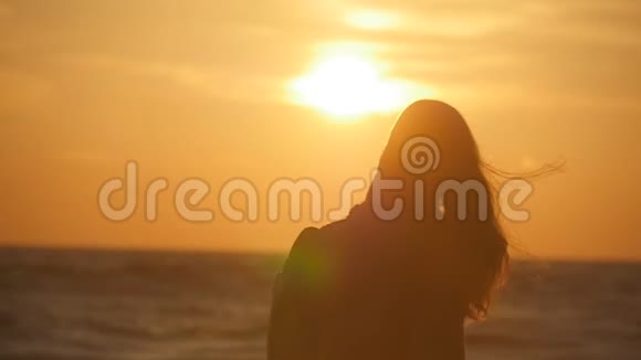 日出时年轻的旅人女子去海边的剪影年轻女游客背着背包在海上行走视频的预览图