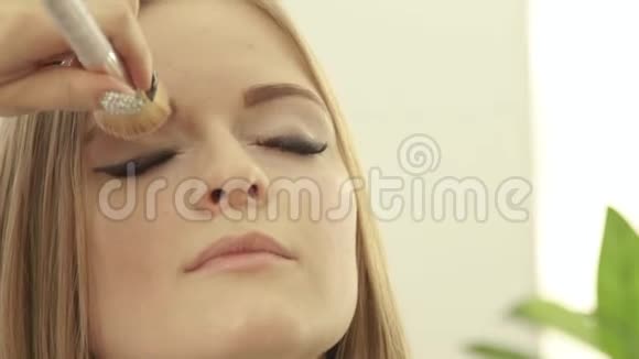 在美容工作室使用化妆品刷来化妆眼睛为女模特做化妆视频的预览图