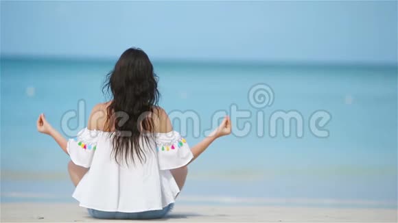 热带度假期间瑜伽位置的漂亮女孩健康的年轻女子坐在瑜伽位置冥想视频的预览图