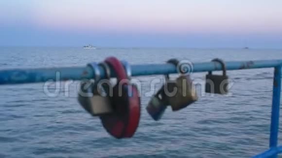 在海和船的背景下挂在桥上的爱情锁视频的预览图