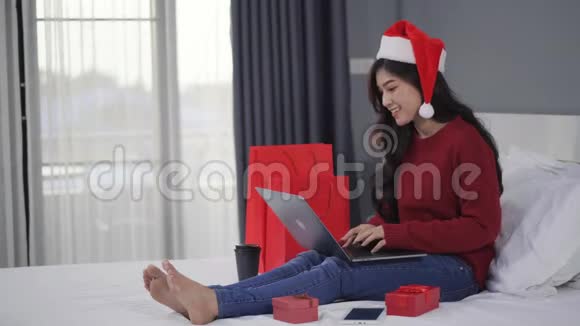 快乐的女人用手提电脑把圣诞礼物放在床上视频的预览图