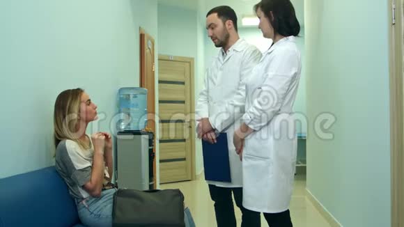 两位医生在医院大厅里和一位女病人谈话视频的预览图