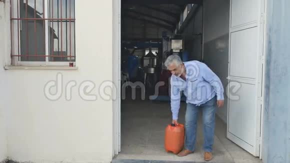 一个年长的人站在工厂门口拿着罐子视频的预览图