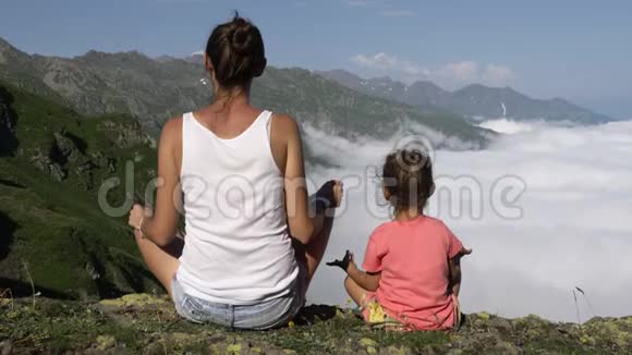 年轻女子带着小可爱的女儿在山顶冥想视频的预览图