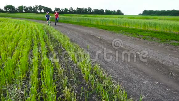两个孩子一起骑自行车在乡村风景中奔跑视频的预览图
