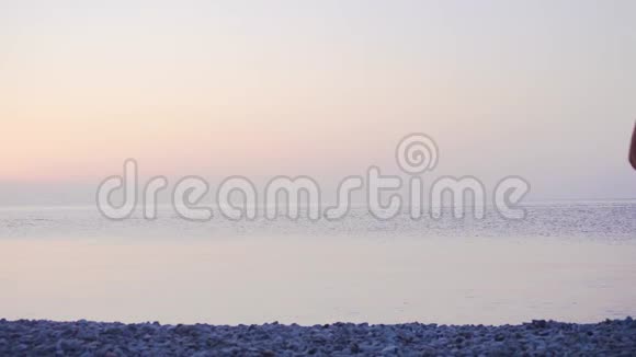 日出时沿着海岸走的年轻女子视频的预览图