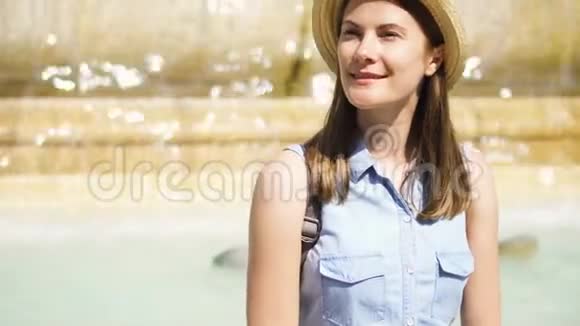 快乐的游客戴着帽子坐在老黄的喷泉上水流不息欧洲度假的女孩视频的预览图
